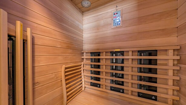 A sauna room with wooden walls and benches, a control panel, and safety signs. - Great apartment with infrared sauna and balcony with a wonderful panoramic view! (Nordseeheilbad Schillig)