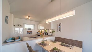 A modern kitchen with a central island, a dining table with benches, and a built-in oven. - Great apartment with infrared sauna and balcony with a wonderful panoramic view! (Nordseeheilbad Schillig)