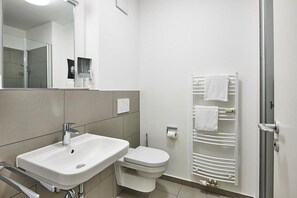 A modern bathroom with a white sink, toilet, and towel rack.