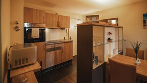Una cocina moderna con armarios de madera, horno empotrado y vitrina con cristalería.