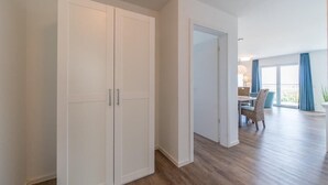 Una habitación amplia con un armario grande, una zona de comedor con mesa y sillas, y vistas al exterior a través de ventanas grandes.