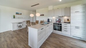 Una cocina moderna con armarios blancos, una isla central e iluminación colgante.