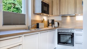 A modern kitchen with white cabinetry, a stainless steel oven, and a coffee maker.