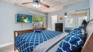 A bedroom with a bed, a ceiling fan, a TV, and a large window. - Near beach, spacious 4bd, pool/waterfront/paddle boards. (Pompano Beach)