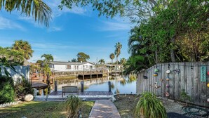 A waterfront property with a dock, a wooden fence with decorative items, and a clear sky. - Near beach, spacious 4bd, pool/waterfront/paddle boards. (Pompano Beach)