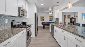 A modern kitchen with granite countertops, stainless steel appliances, and a central island. - Near beach, spacious 4bd, pool/waterfront/paddle boards. (Pompano Beach)