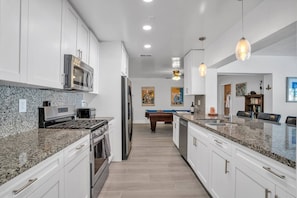 A modern kitchen with granite countertops, stainless steel appliances, and a central island.