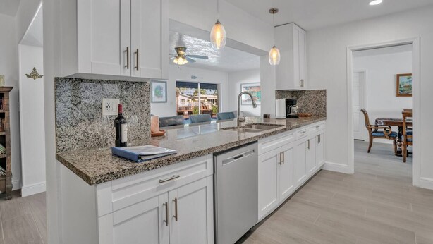 A modern kitchen with granite countertops, white cabinetry, and pendant lighting. - Near beach, spacious 4bd, pool/waterfront/paddle boards. (Pompano Beach)