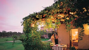 A cozy outdoor dining area with a table and chairs, surrounded by lush greenery and a building with a warm light. - Residence Baia delle Palme (Pula)