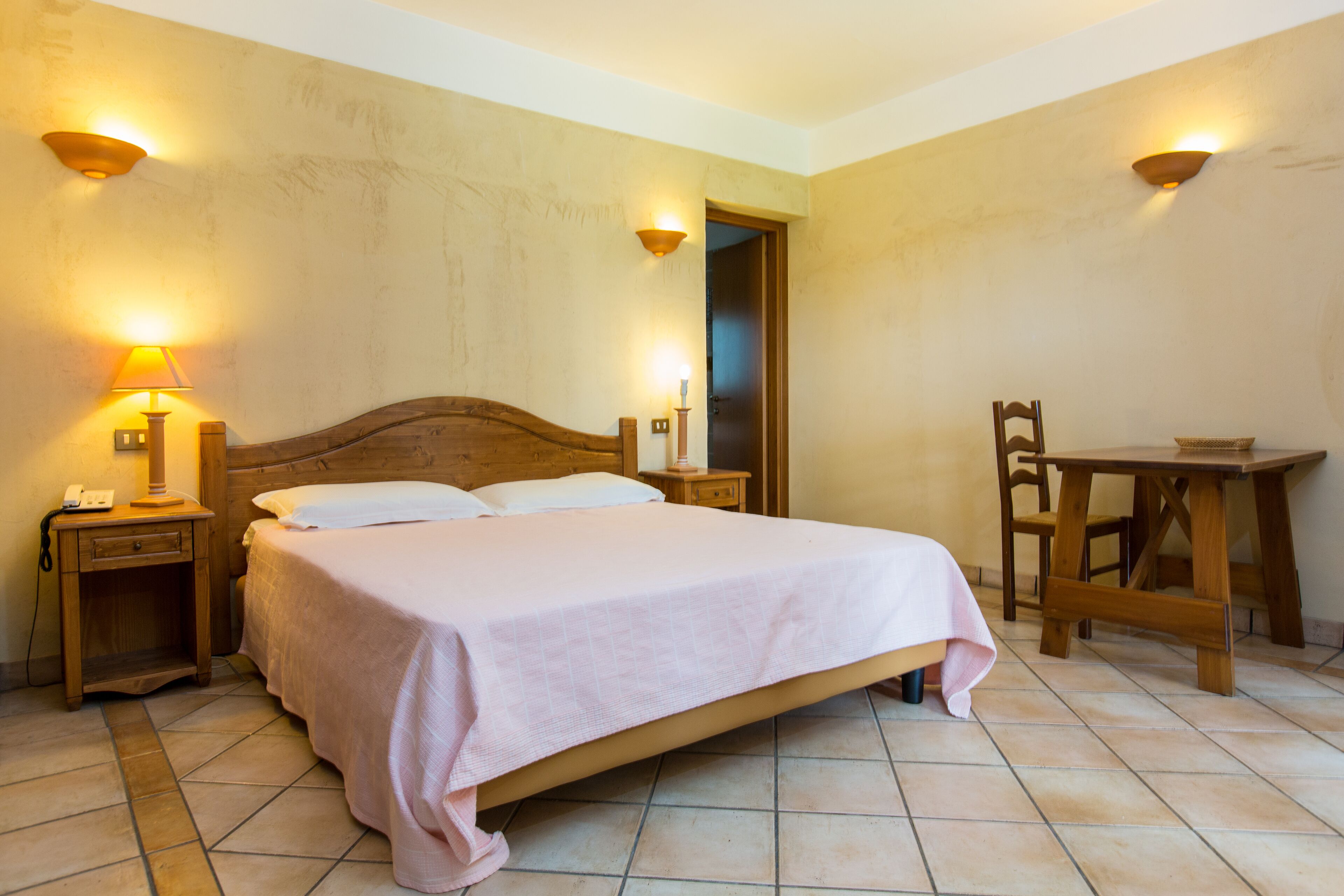 A bedroom with a wooden bed, bedside tables, a chair, and a small table.