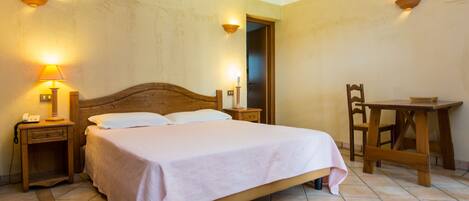 A bedroom with a wooden bed, bedside tables, a chair, and a small table.