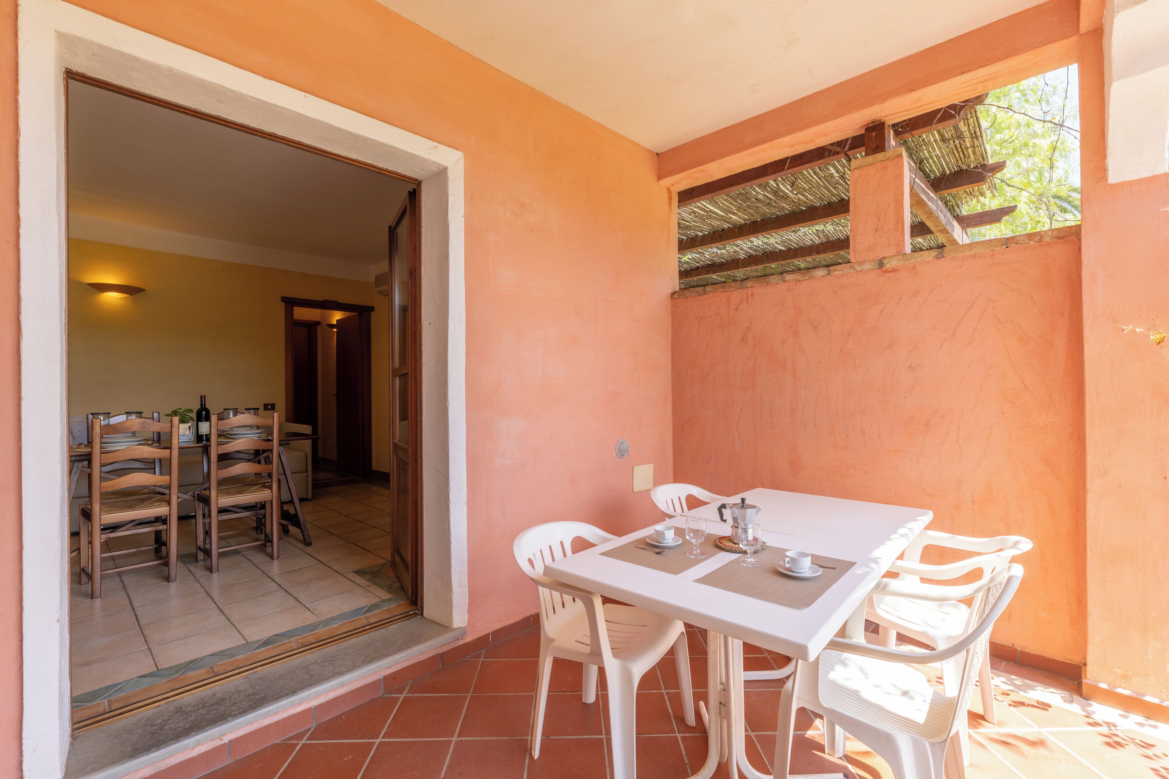 A dining area with a table and chairs, a doorway leading to another room, and a tiled floor.