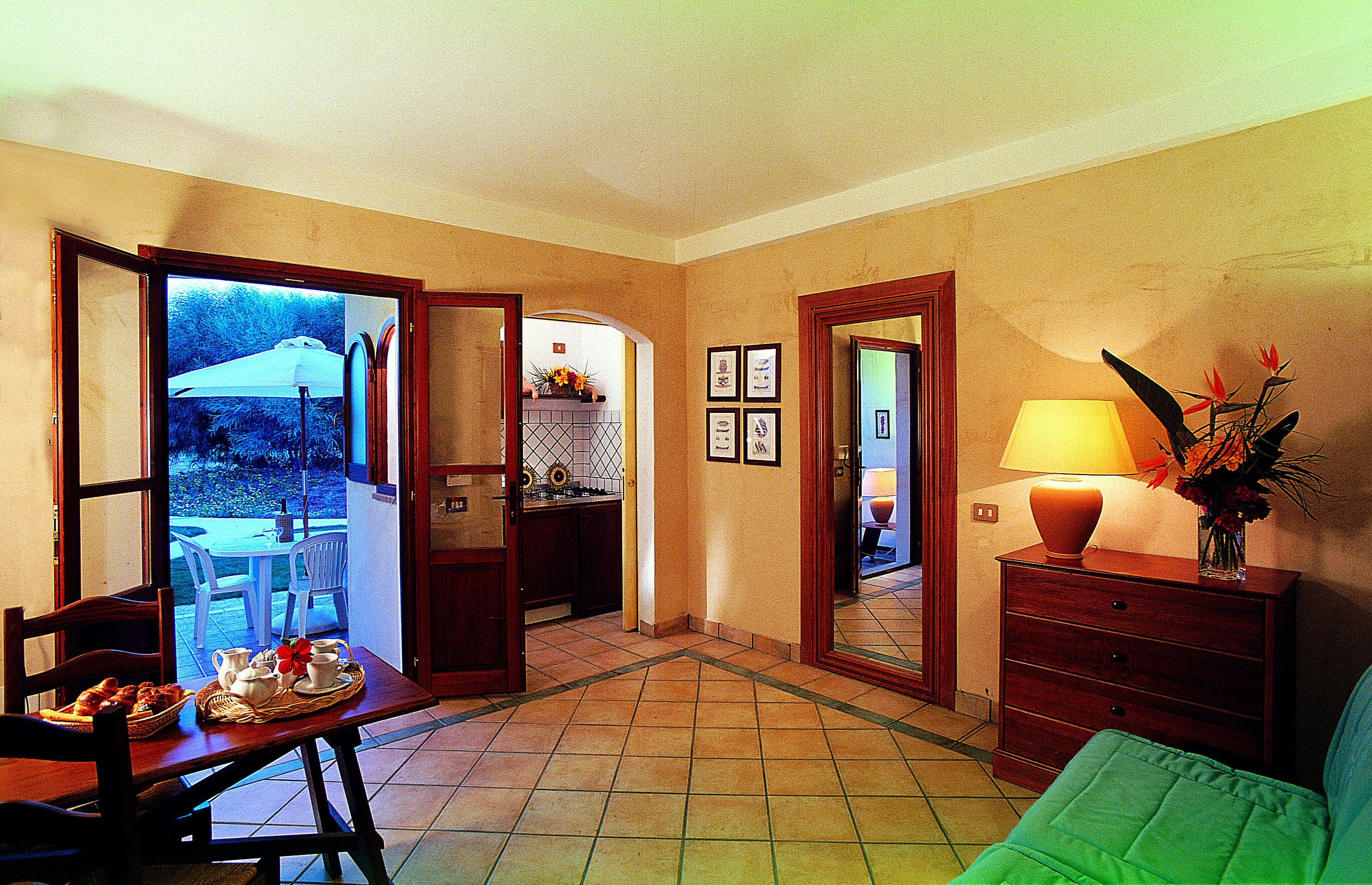 A room with a dining area, a sofa, a lamp, and a dresser.