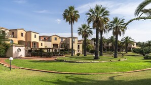 A courtyard with palm trees, a pool, and a building with balconies. - Residence Baia delle Palme (Pula)