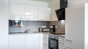 Una cocina moderna con armarios blancos, microondas integrado, cafetera y estufa.