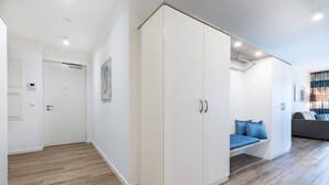 Un apartamento moderno con un armario amplio, una zona de estar con un cojín azul y un sofá gris.