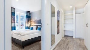 Un dormitorio moderno con una cama grande, una mesita de noche y un ventanal con cortinas.
