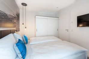 Une chambre d’hôtel moderne dotée d’un grand lit, d’un téléviseur à écran plat fixé au mur et d’une porte donnant sur un placard.