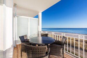 A balcony with wicker chairs and a table, overlooking a beach and the sea. - Ferienapartment Direkt am Ostseestrand mit Balkon und Einmalig-schönem Meerblick (Ostseeheilbad Großenbrode)