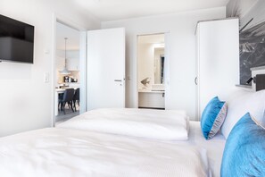Una habitación de hotel moderna con una cama, un escritorio y un baño visible a través de una puerta abierta.