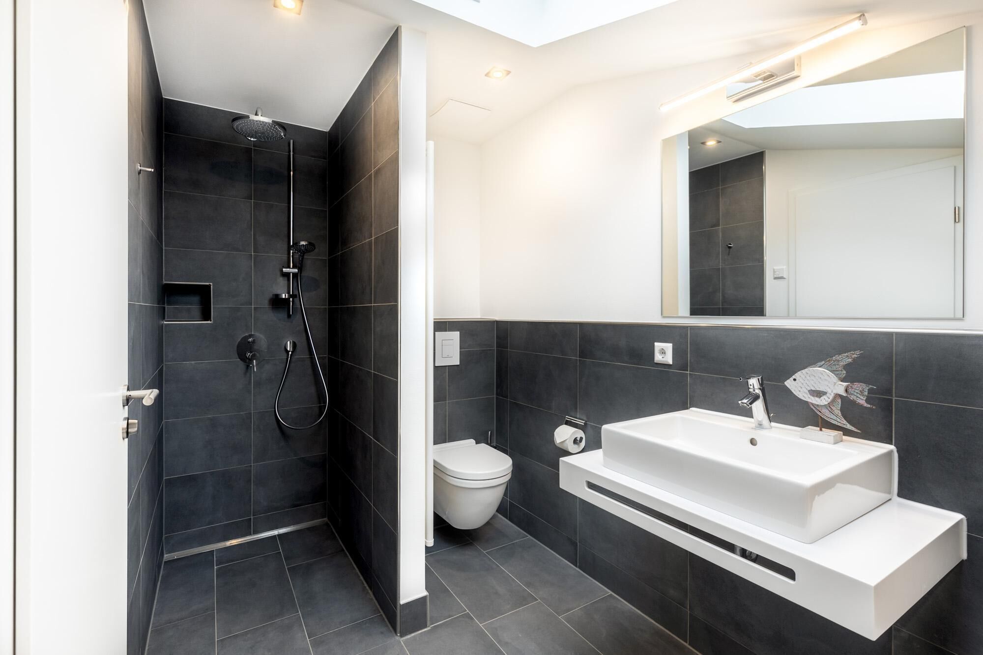 Ein modernes Badezimmer mit begehbarer Dusche, Toilette und Waschbecken mit Spiegel darüber.