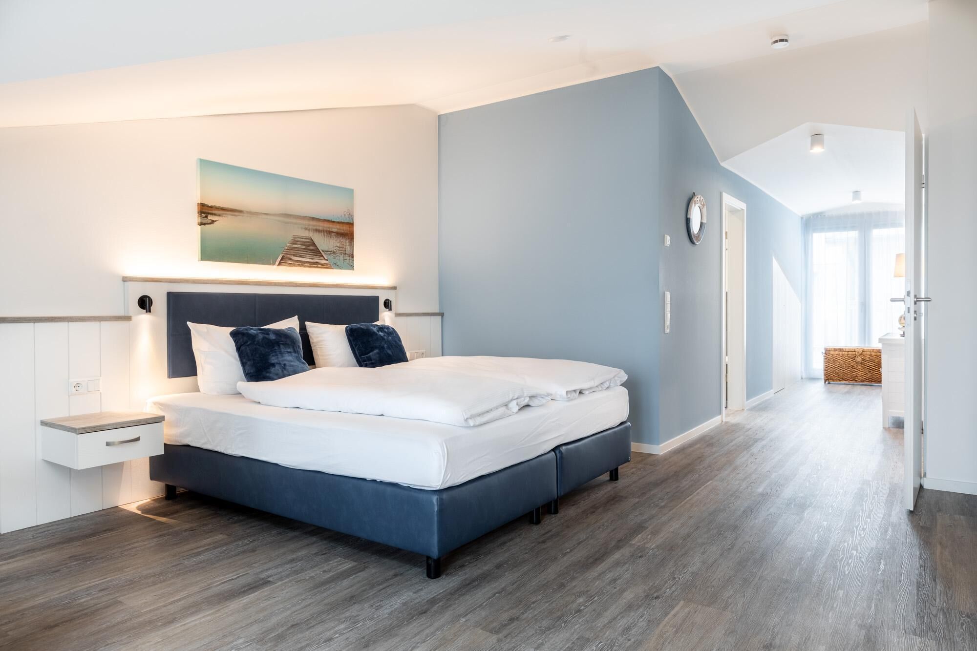 A modern bedroom with a bed, bedside table, and a painting on the wall.