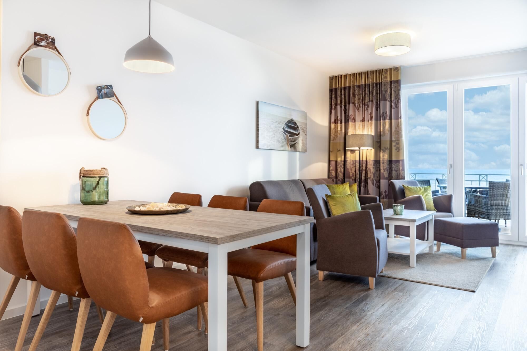 Sala de estar moderna com área de jantar, com mesa de madeira, cadeiras de couro, sofá e varanda com vista.