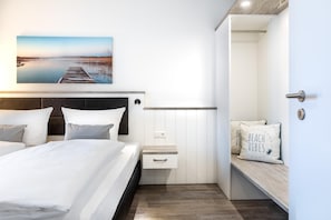 Une chambre d’hôtel moderne avec un lit, une table de chevet et un banc agrémenté de coussins.