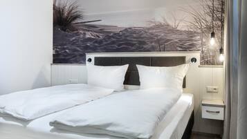 Ein modernes Schlafzimmer mit einem Bett, einem Nachttisch und einer Wandmalerei, die eine Strandansicht zeigt.