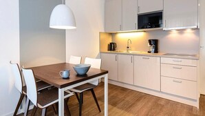 Une cuisine moderne avec des meubles blancs, un four à micro-ondes, une machine à café et une table à manger avec des chaises.