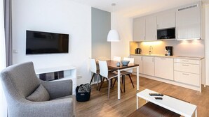 Un salon moderne doté d’un téléviseur à écran plat, d’une table à manger avec des chaises, d’un canapé et d’une table basse.
