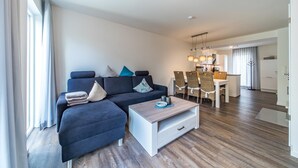 Un salon moderne avec un canapé, une table basse et un coin repas avec des chaises.