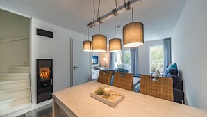 Un espace repas moderne avec une table en bois, des chaises en osier et des luminaires suspendus.
