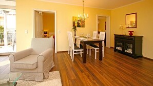 Un comedor con una mesa y sillas de madera, una araña y un aparador con puertas de vidrio.