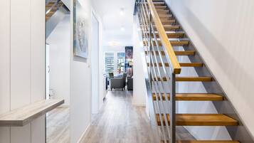 Eine moderne Treppe mit Holzboden und Metallgeländern, die zu einem Wohnbereich mit Blick auf die Stadt führt.