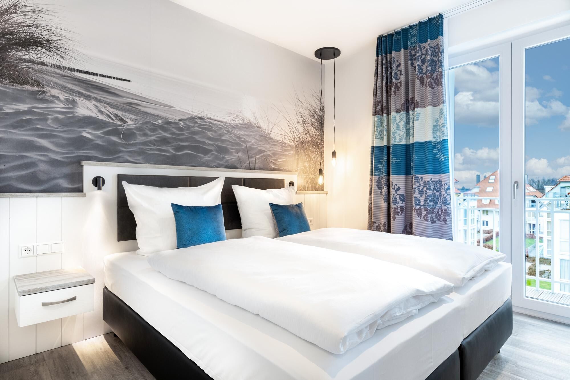 Ein modernes Schlafzimmer mit einem großen Bett, einem Bettkopf mit strukturierter Wand, einem Nachttisch und Blick auf die Stadt durch ein großes Fenster.