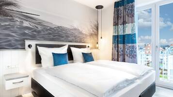 Ein modernes Schlafzimmer mit einem großen Bett, einem Bettkopf mit strukturierter Wand, einem Nachttisch und Blick auf die Stadt durch ein großes Fenster.