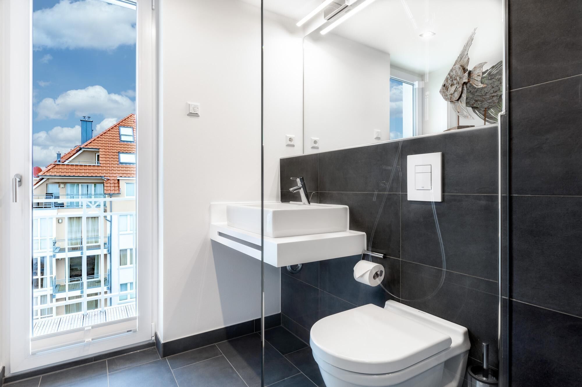 Een moderne badkamer met toilet, wastafel en douche.