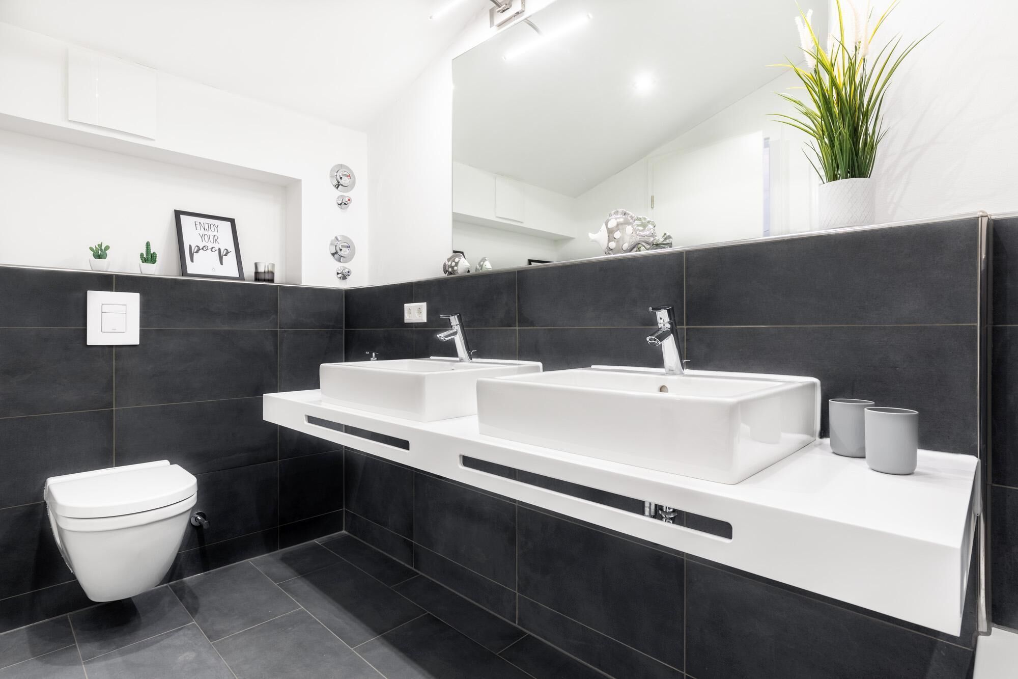 A modern bathroom with two sinks, a toilet, and a mirror.