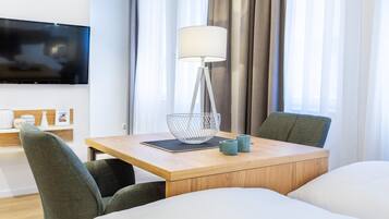 Ein Hotelzimmer mit Holztisch, zwei Stühlen, Fernseher, Lampe und Bett.