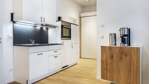 Une cuisine moderne avec des meubles blancs, une hotte en acier inoxydable et un four encastré.