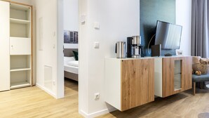 Une chambre d’hôtel moderne équipée d’un meuble en bois, d’un téléviseur à écran plat et d’une machine à café.