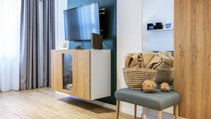 Een moderne woonkamer met een flatscreen televisie op een houten kast, een bank met geweven manden en een houten kledingkast.