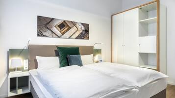 Ein modernes Schlafzimmer mit einem großen Bett, einem Nachttisch mit Lampe, einem Kleiderschrank und einem Wandbild.