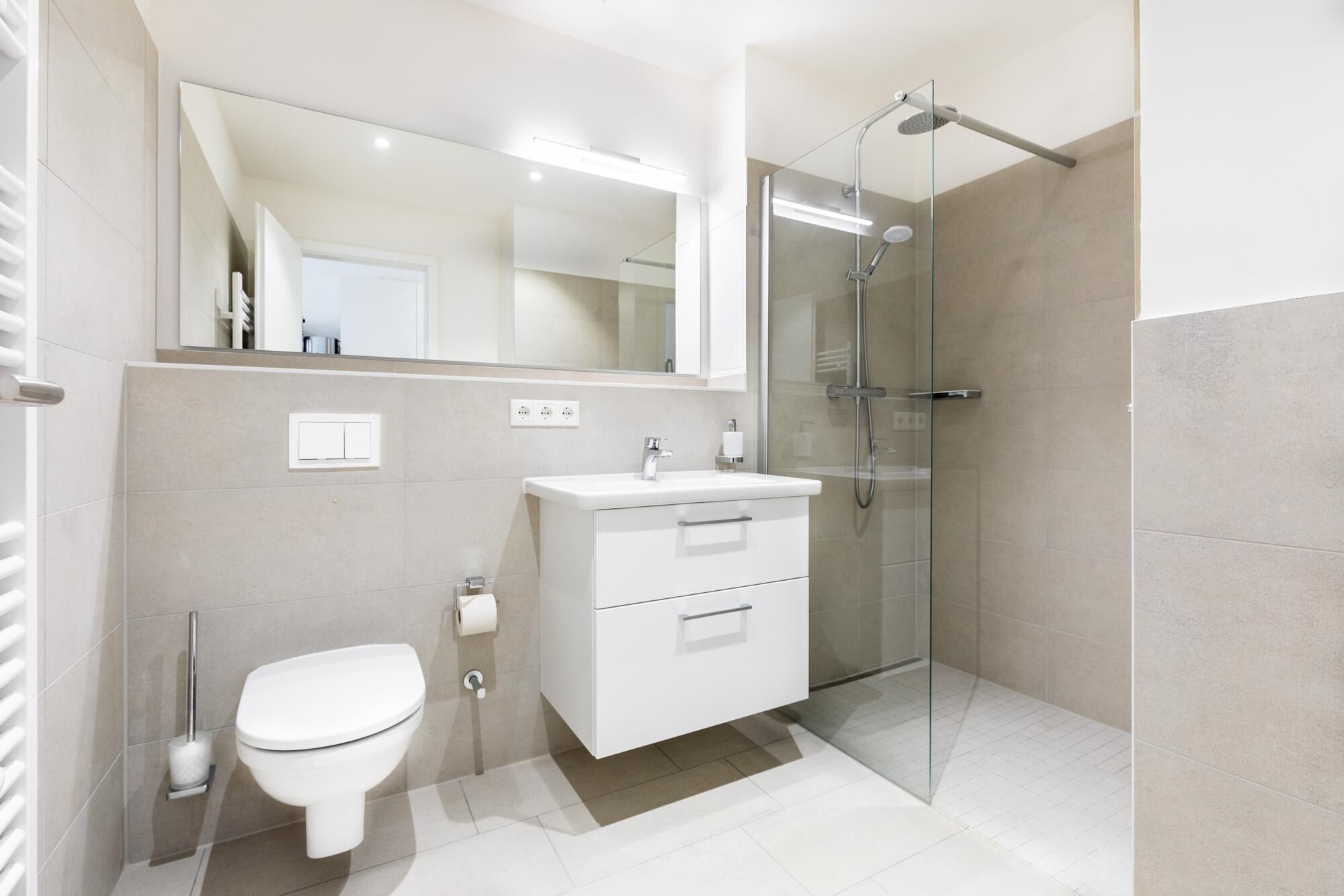 A modern bathroom with a toilet, sink, and glass shower enclosure.