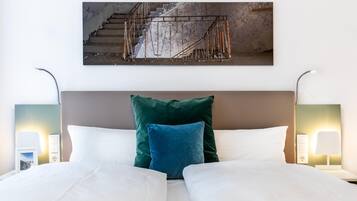 A hotel room with a bed, two bedside lamps, and a painting of a staircase.
