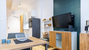 Una cocina moderna con zona de comedor, televisor de pantalla plana y cafetera.