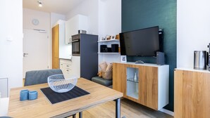 A modern kitchen with a wooden table, a TV, and built-in appliances.