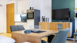 A modern kitchen with white cabinets, a built-in oven, and a flat-screen TV mounted on the wall.