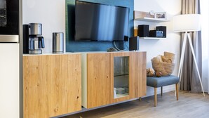 A modern living area with a flat-screen TV, coffee maker, and a wooden cabinet with a glass door.